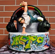 there is a cake that has a figure on top of it with headphones in front of a brick wall