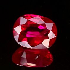 a large red diamond sitting on top of a table next to a black background,