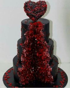 a three tiered cake with red decorations on the top and bottom, decorated in black icing