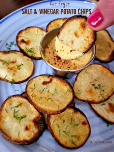 a blue plate topped with potato chips covered in butter and seasoning next to a small bowl of dipping sauce