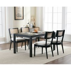 a dining room table with chairs and a rug in front of the table is shown