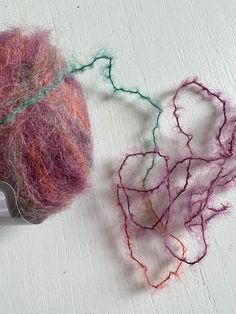 two balls of yarn sitting next to each other on a white surface with scissors and thread