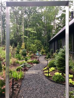 a gravel path leading to a building surrounded by trees