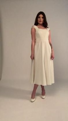 a woman in a white dress is posing for a photo with her hands on her hips