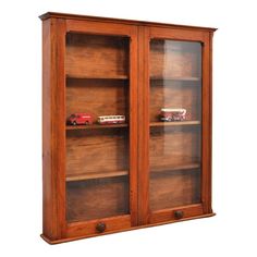 a wooden bookcase with two glass doors on the front and bottom shelves, both holding toy cars