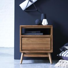 a night stand with a lamp and books on it next to a blue wall in a room