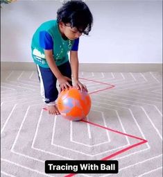 a little boy playing with a ball on the floor