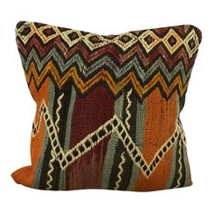 an orange and brown pillow with geometric designs on it's sides, against a white background