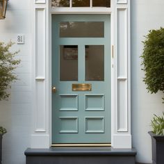 a blue front door on a white house with potted plants in the foreground