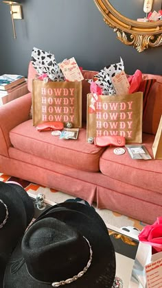 two hats and bags sitting on a couch in front of a wall with a mirror