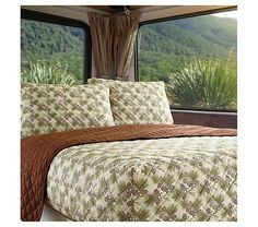 a bed in a room with a large window and mountains out the back ground behind it