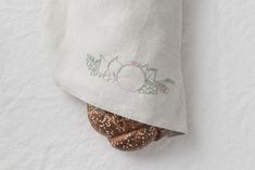 a bagel with sprinkles is wrapped in a linen napkin on a white surface