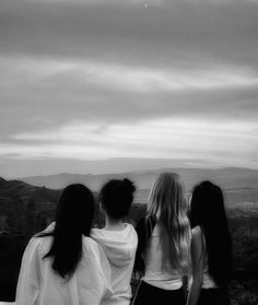 three women standing on top of a hill looking at the sky