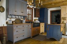 an old fashioned kitchen with blue cabinets and wood floors