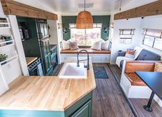 a kitchen and living room in a mobile home with wood flooring, green cabinets and white walls