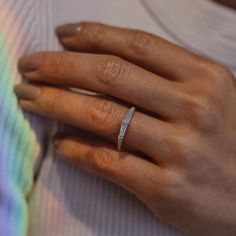 a woman's hand with a diamond ring on her left hand, wearing a striped shirt