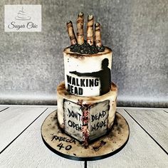 a three tiered cake with writing on it and zombie hand coming out of the top