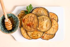 a white plate topped with sliced cucumbers next to a bowl filled with honey