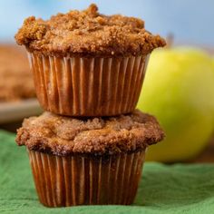 two muffins stacked on top of each other with an apple in the background