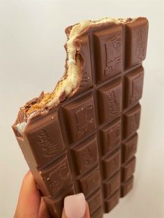 a hand holding a chocolate bar with white frosting