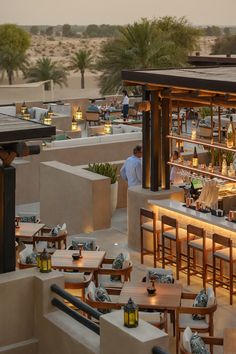 an outdoor dining area with tables, chairs and people at the bar in the desert