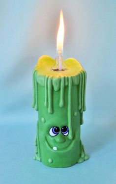 a green candle that has some kind of thing on it's face and eyes