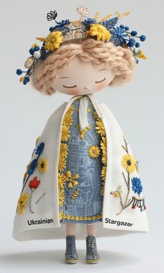 the doll is wearing a blue and white dress with flowers on it's head