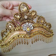 a gold tiara is being held by someone's hand