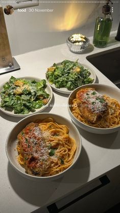 three bowls of food are sitting on a counter