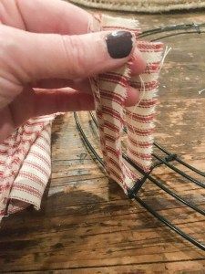 a hand holding a piece of fabric on top of a wooden table next to wire