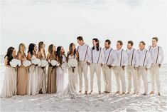 a group of people standing next to each other on top of a sandy beach in front of the ocean