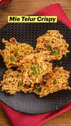 some food is on a black plate with a red napkin next to it and the words mie telur crispy