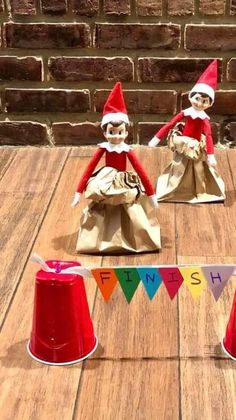 two elfs sitting next to each other on top of a wooden table with paper cones