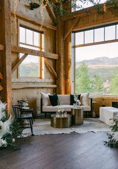 a living room filled with lots of furniture next to large windows on top of a wooden floor