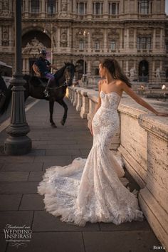 a woman in a wedding dress standing next to a horse on a bridge near a building