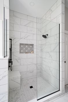 a walk in shower sitting next to a white tiled wall and floor with a glass door