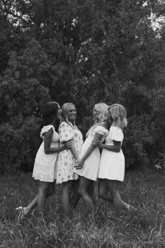 black and white photograph of four girls hugging each other in the middle of a field