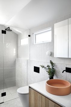 a bathroom with a sink, toilet and shower stall in the background is a white tiled wall