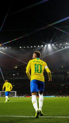 a soccer player in yellow and blue is on the field during a game at night