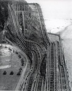 black and white photograph of an aerial view of a train track near the water's edge