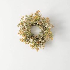 a small wreath with white and yellow flowers hanging on a wall in the shape of a circle