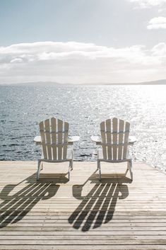 two chairs sitting on top of a wooden dock