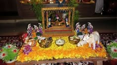 there are many small figurines on the table in front of this shrine that is decorated with flowers and leaves