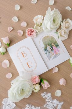 an open book on a table surrounded by flowers and confetti with the letter b