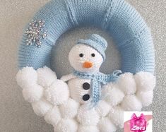 a knitted snowman wreath hanging on the wall with a snowman in it