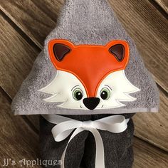 a gray and orange hat with a fox face on the front is hanging from a wooden wall