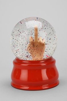 a snow globe with a hand in it on top of a red base and sprinkles all over the surface