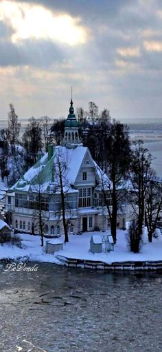 a large white building sitting on top of a snow covered hill next to a body of water