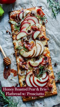 an apple and rosemary flatbread on a piece of parchment paper next to some apples