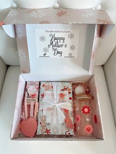 an open gift box filled with personal care items on top of a white couch next to a pink heart